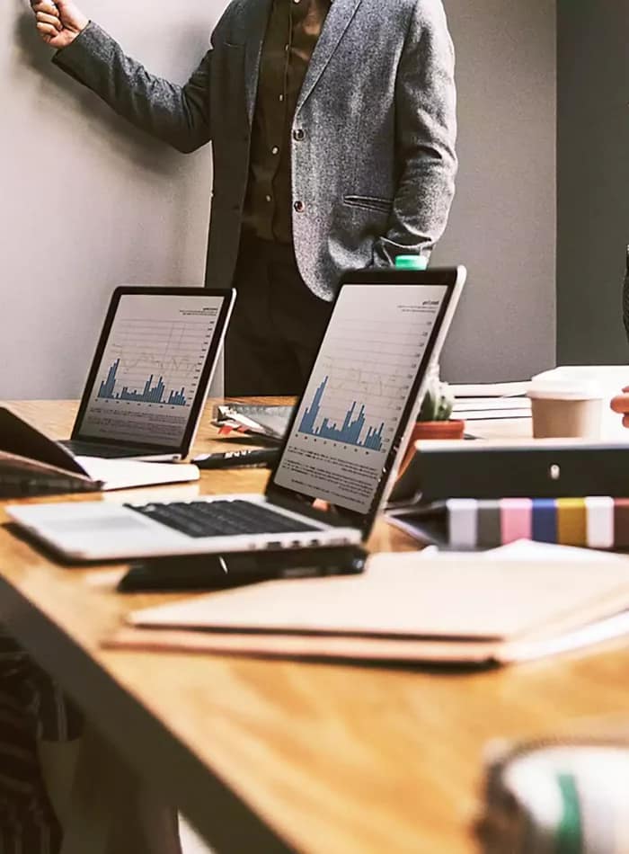 ICV Consultant Dubai - A group of people is sitting together at a table, each with their laptops open. They appear to be engaged in work or collaboration within an indoor office setting. The environment includes typical office furniture such as desks and chairs, with a wall backdrop.